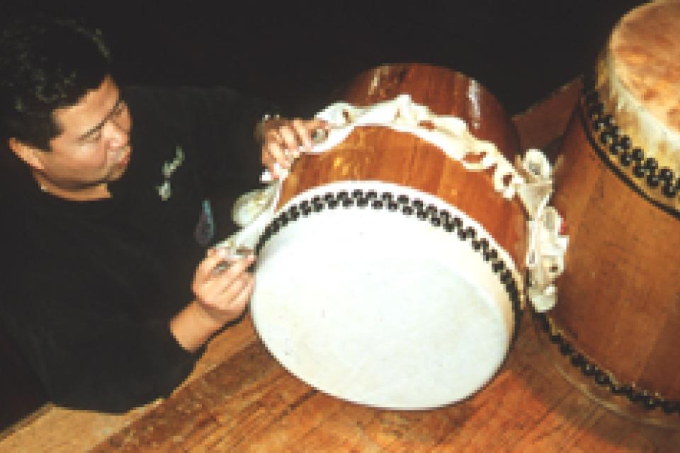 Man trimming the excess skin from a freshly skinned taiko